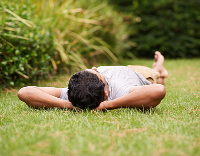 Buy stock photo A young man lying on the grass with his hands behind his head