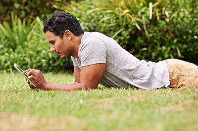 Buy stock photo Man, outside and tablet on grass, browse and watching social media or memes for entertainment in nature. Male person, backyard and tech to relax, scroll and vacation at home or house for peace 