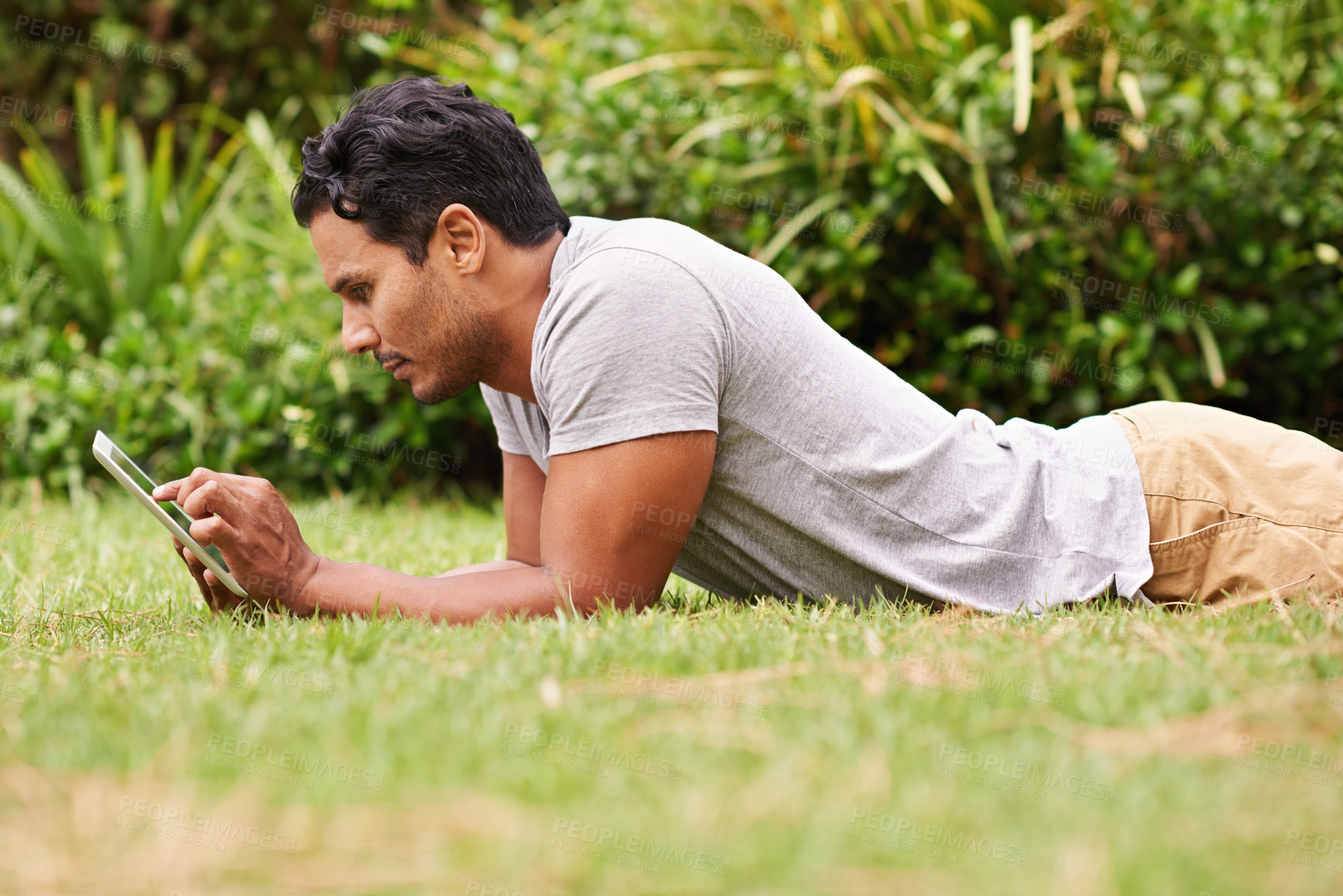 Buy stock photo Man, outside and tablet on grass, browse and watching social media or memes for entertainment in nature. Male person, backyard and tech to relax, scroll and vacation at home or house for peace 