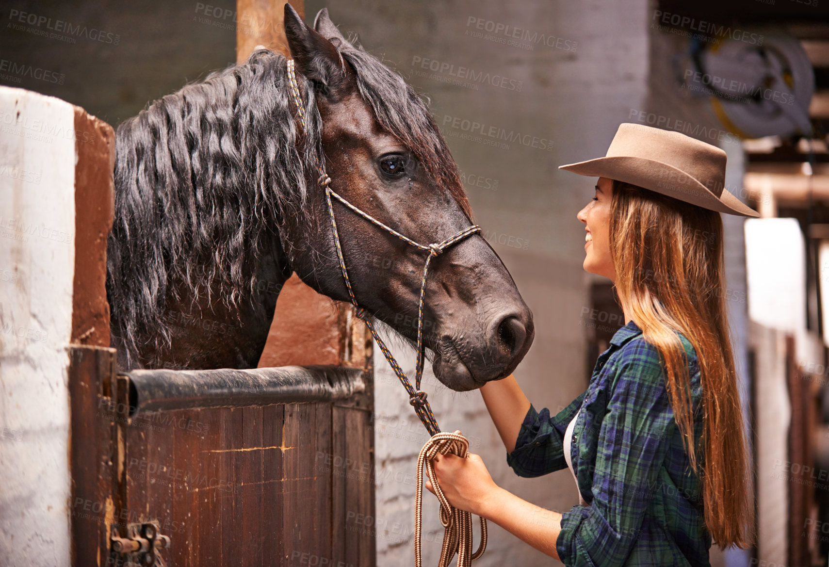 Buy stock photo An attractive young cowgirl bonding with her horse in the stable