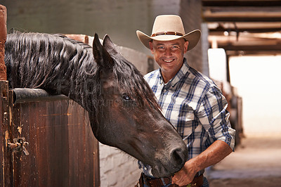 Buy stock photo A caring ranch hand attending to a horse in the stable