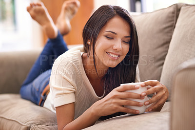 Buy stock photo Shot of a beautiful young woman lying on the sofa at home