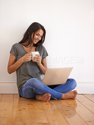 Buy stock photo Apartment, laptop and woman with coffee on floor by wall background in home with smile and mug. Happiness, female person and girl watching movies on site of app online with technology and internet
