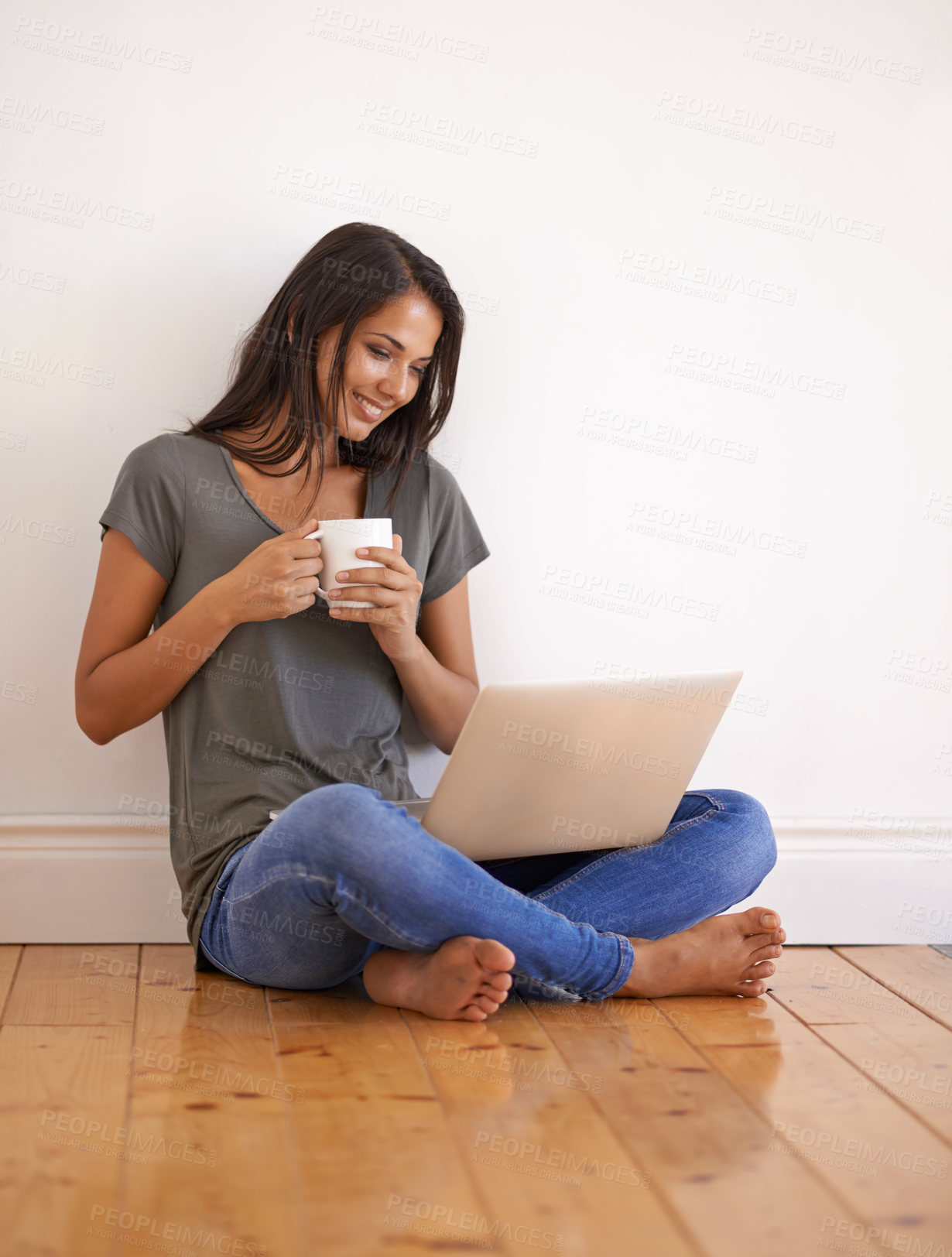 Buy stock photo Apartment, laptop and woman with coffee on floor by wall background in home with smile and mug. Happiness, female person and girl watching movies on site of app online with technology and internet