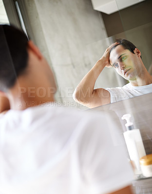 Buy stock photo Cropped shot of a young man looking at himself in the mirror