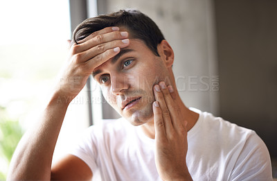 Buy stock photo Cropped shot of a young man feeling his face for stubble
