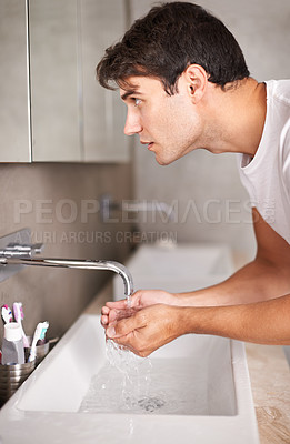 Buy stock photo Shot of a man looking in the mirror while holding his hands underneath a tap