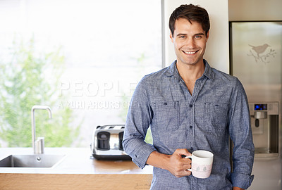 Buy stock photo Portrait of a handsome young man standing in his kitchen with a cup of coffee