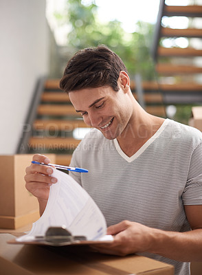 Buy stock photo A happy young man signing for a delivery of packed cardboard boxes