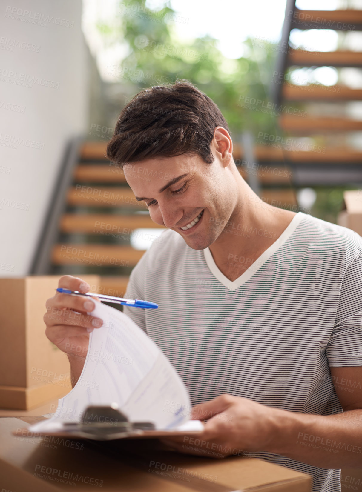 Buy stock photo A happy young man signing for a delivery of packed cardboard boxes