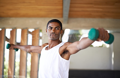 Buy stock photo A handsome young african man lifting dumbells indoors