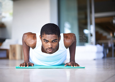 Buy stock photo Shot of a young man doing push ups on an exercise mat