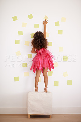 Buy stock photo Rear view shot of a little girl sticking notes to the wall