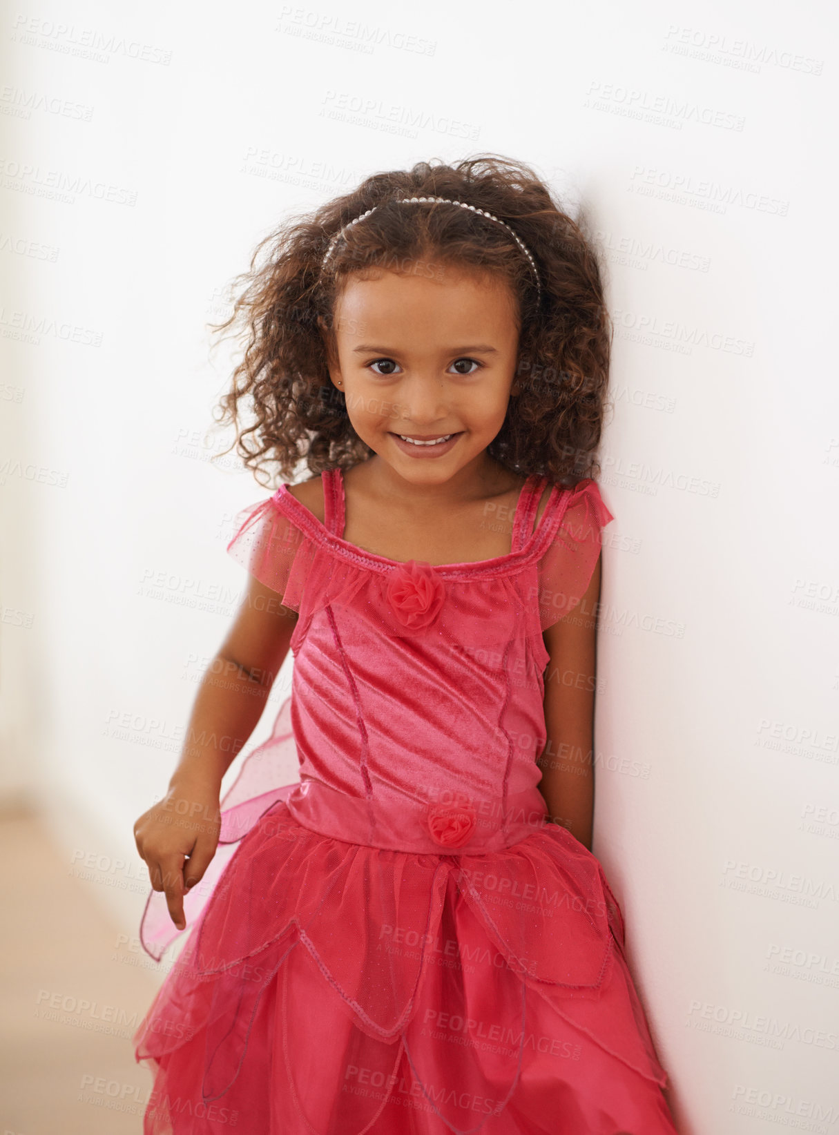 Buy stock photo Girl, child and portrait or smile in fashion with confidence, wellness and headband for fairy aesthetic in home. Kid, face and happiness with relax by wall in living room with dress and curly hair