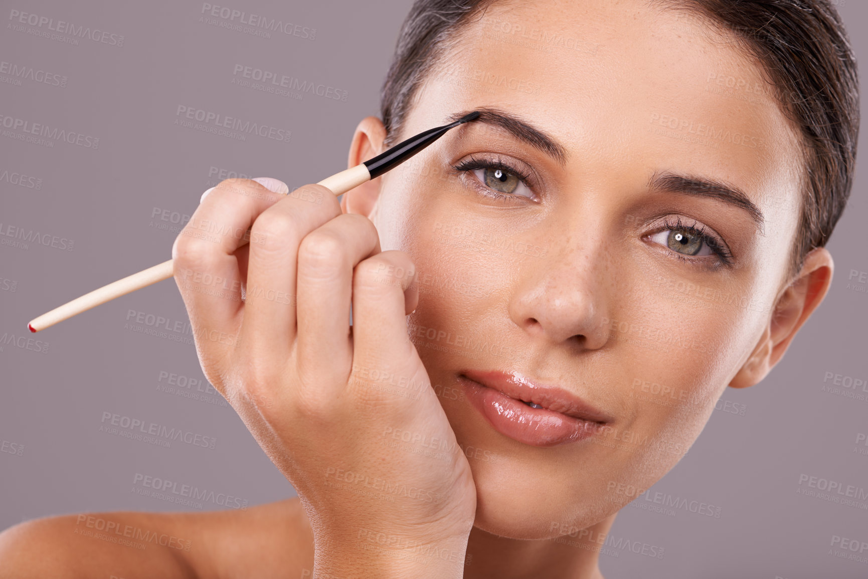 Buy stock photo Woman, beauty and eyebrow brush with makeup, portrait and studio for glamour and radiance and lip gloss. Female person, blush and foundation in grey background, sexy and attractive confidence