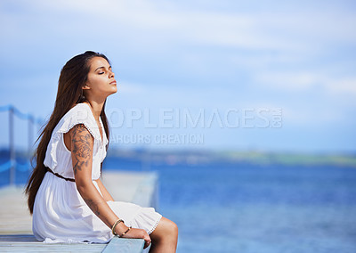 Buy stock photo Cropped shot of a gorgeous tattooed young woman sitting on a pier