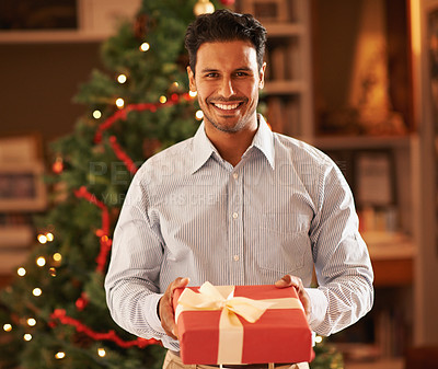 Buy stock photo Cropped shot of a cheerful young man holding out a christmas gift