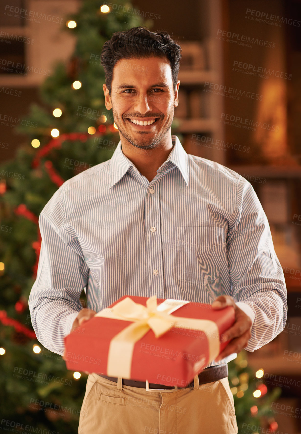 Buy stock photo Happy man, portrait and Christmas tree with gift box for present, festive or December celebration at home. Male person with smile for season of giving, thank you or tradition in living room at house