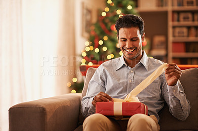Buy stock photo Shot of a handsome young man opening a christmas present