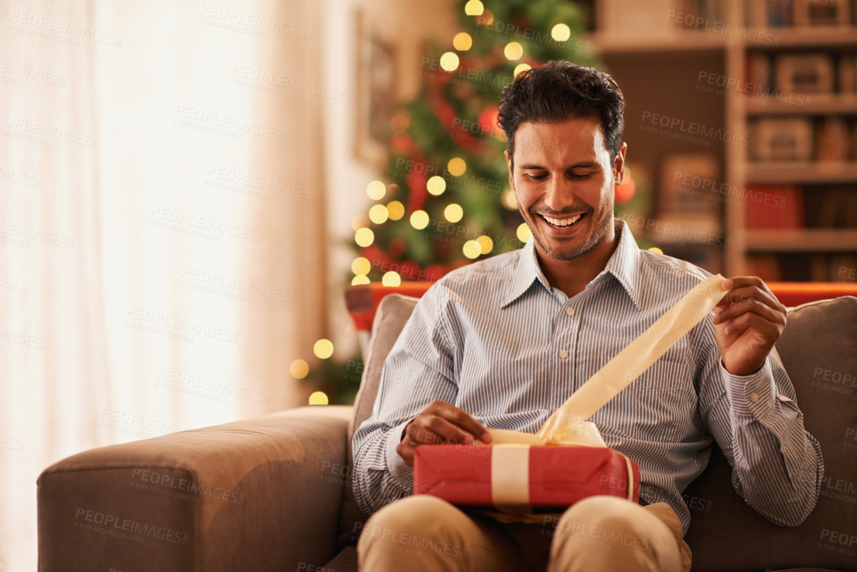 Buy stock photo Shot of a handsome young man opening a christmas present