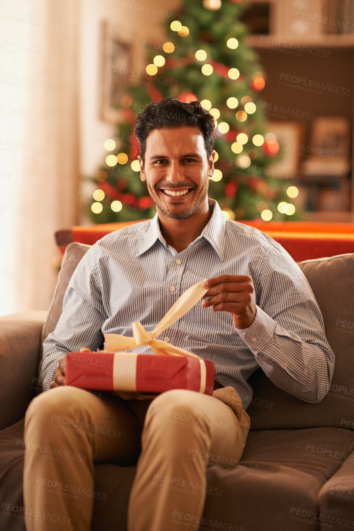 Buy stock photo Happy man, portrait and Christmas tree with gift box on sofa for present, festive or December celebration at home. Male person with smile for giving, thank you or tradition in living room at house