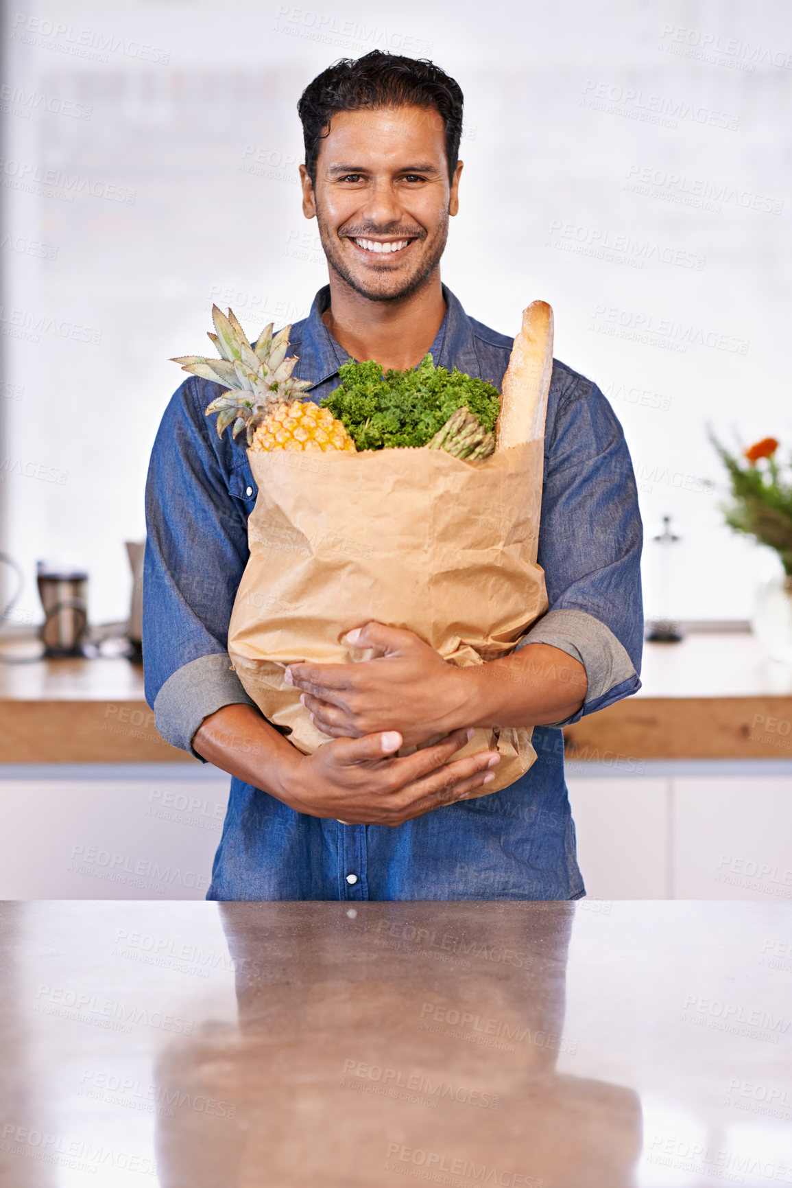 Buy stock photo Portrait of a handsome man holding a shopping bag of healthy food in his arms