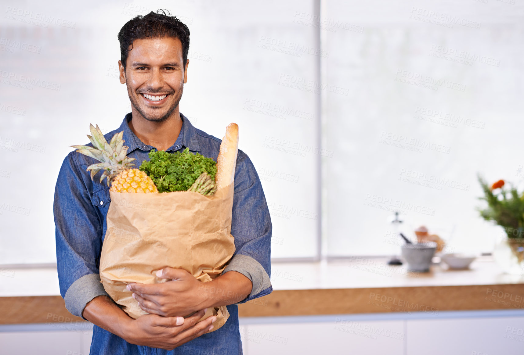 Buy stock photo Groceries, bag and portrait of man with healthy food in kitchen for nutrition, diet or cooking in home. Happy, customer and vegan person with a smile for fruits, vegetables and fresh bread in house