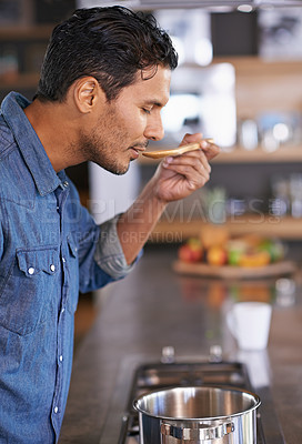Buy stock photo Shot of a handsome man tasting food while he&#039;s cooking at home