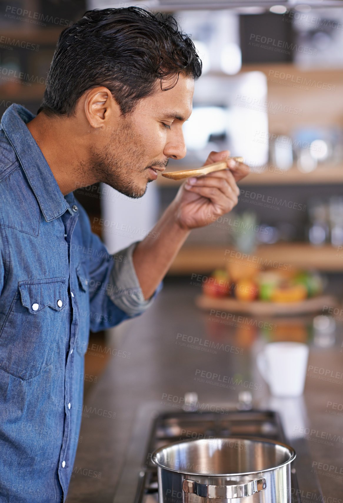 Buy stock photo Shot of a handsome man tasting food while he&#039;s cooking at home