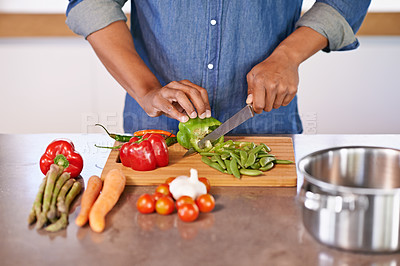 Buy stock photo Cropped view of a man chopping some fresh vegetables on the kitchen counter
