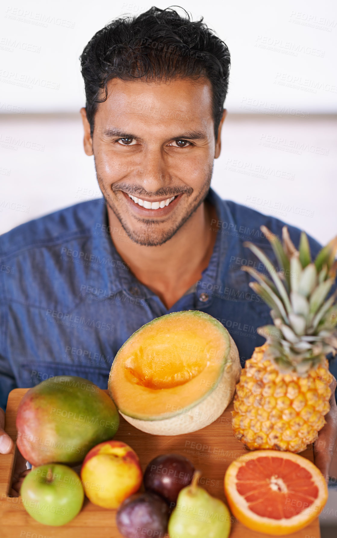 Buy stock photo Portrait of a handsome man holding up a chopping board full of fruit