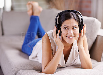 Buy stock photo Happy woman, headphones and listening to music on sofa for thinking, comfort or relaxing at home. Female lying on living room couch with headset for audio sound track or relax on holiday break