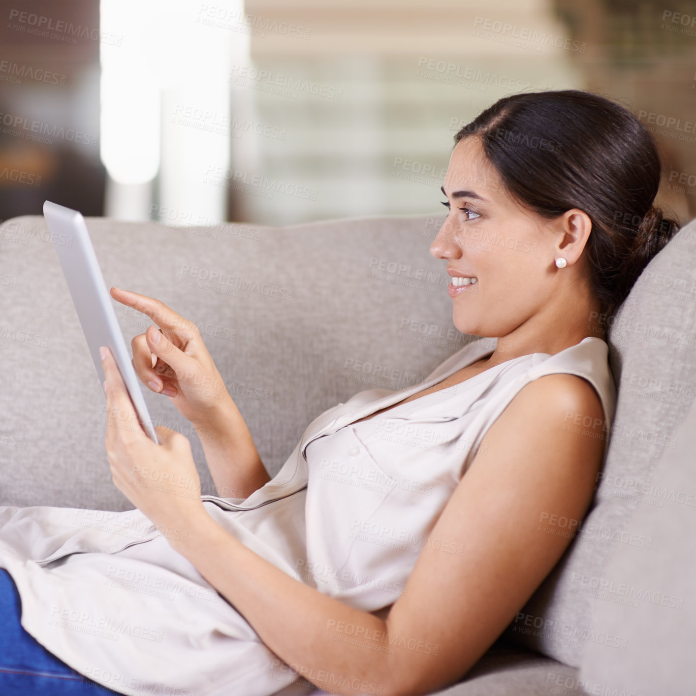 Buy stock photo Happy woman, tablet and relax on living room sofa for streaming, browsing or social media at home. Female relaxing on technology for online entertainment, app or research lying on lounge couch