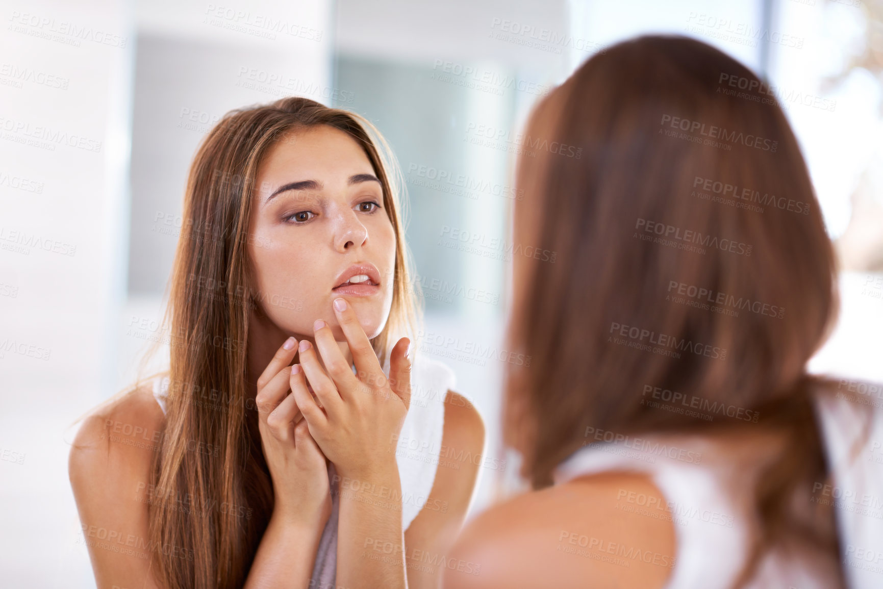 Buy stock photo Over the shoulder shot of an attractive young woman looking at her reflection in a mirror