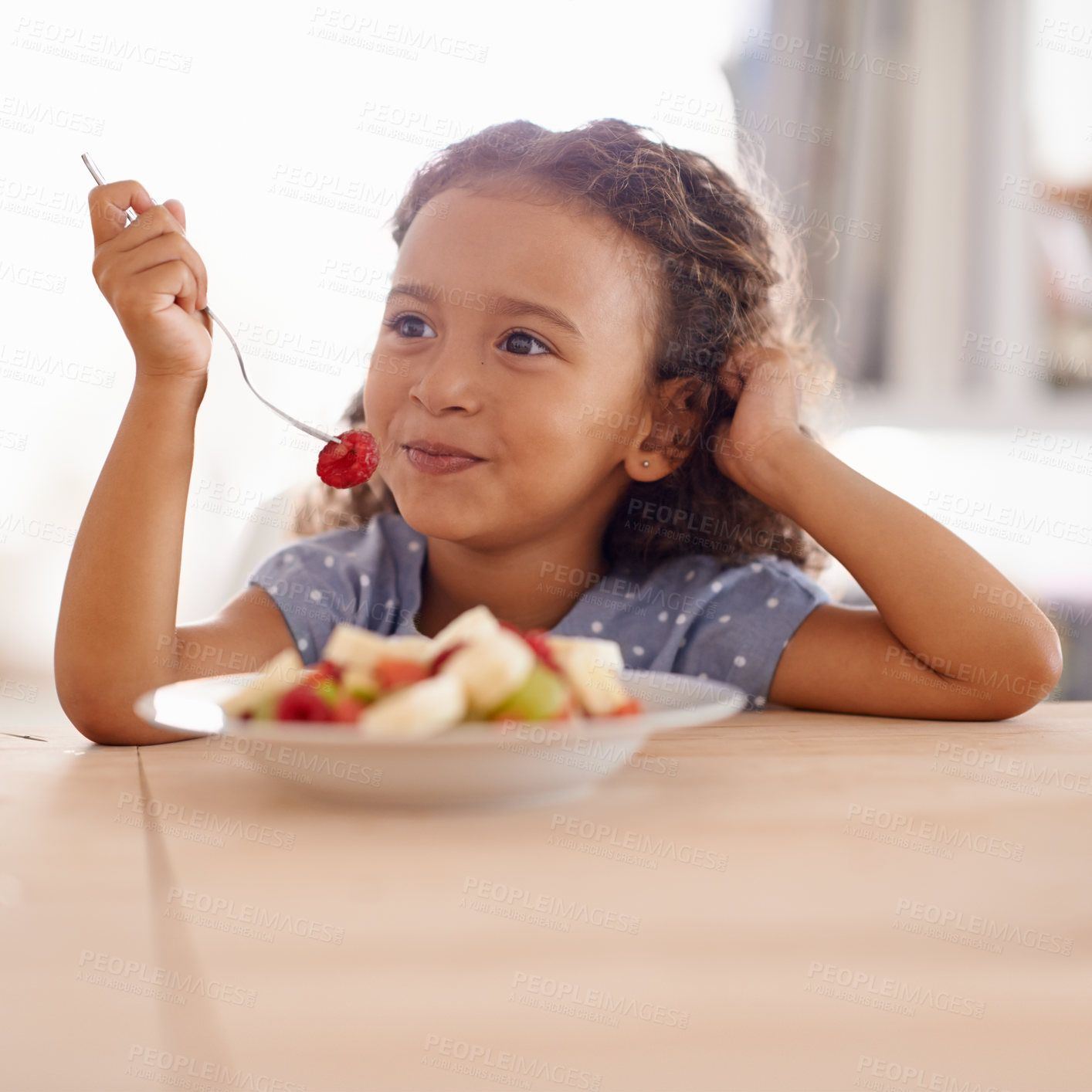 Buy stock photo Shot of a cute little girl eating fruit salad at a table