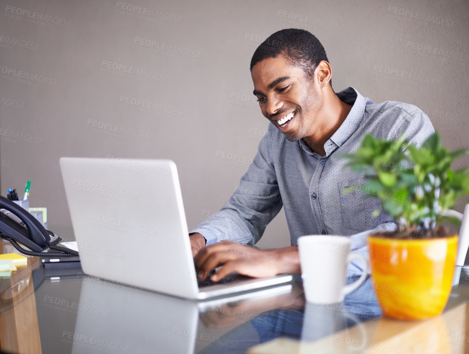 Buy stock photo Shot of a handsome young man happily working on his laptop at home