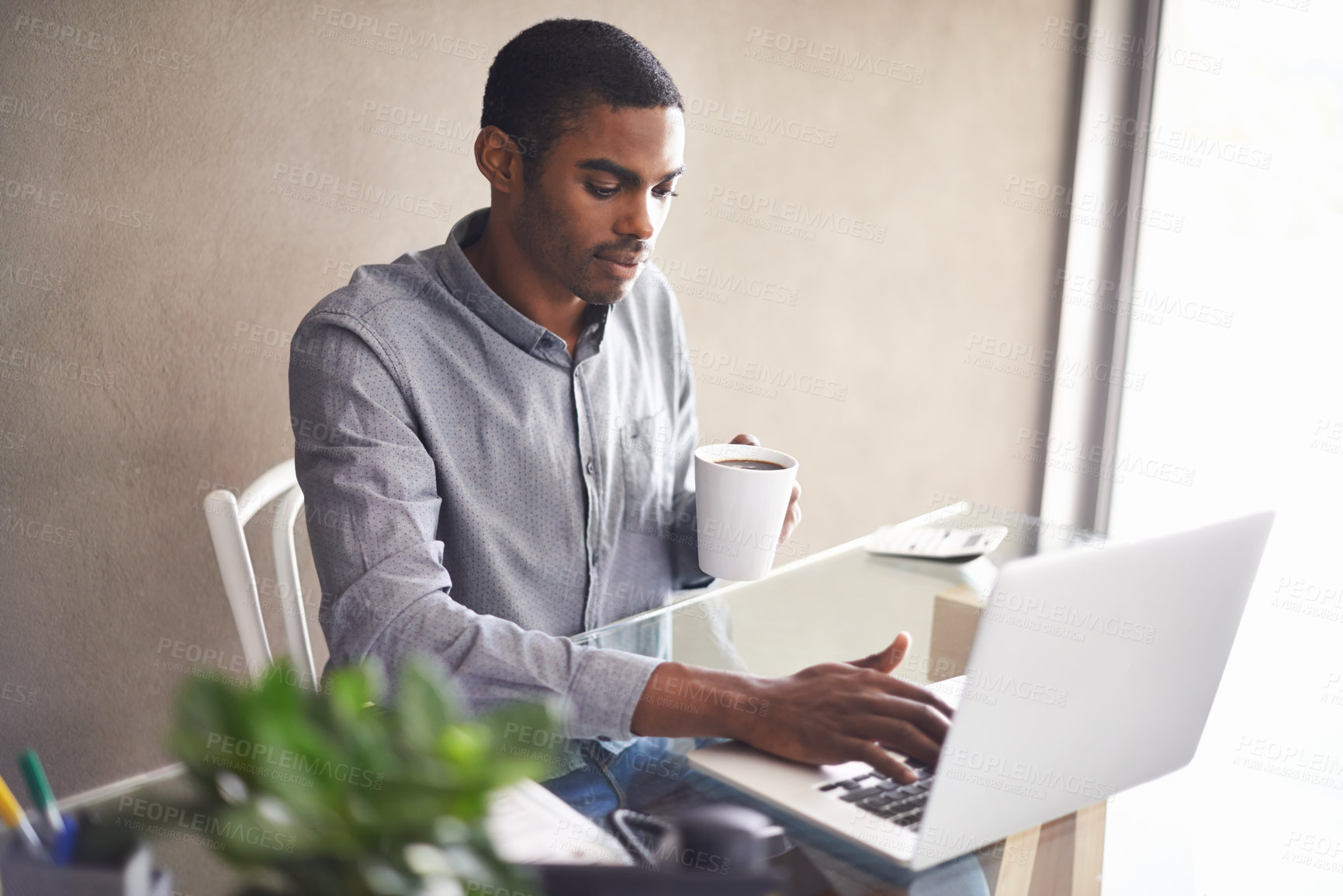 Buy stock photo Laptop, drinking coffee and black man in home office for business, remote work or typing email. Tea, computer and serious freelancer at desk for accounting, bookkeeping or calculation on internet