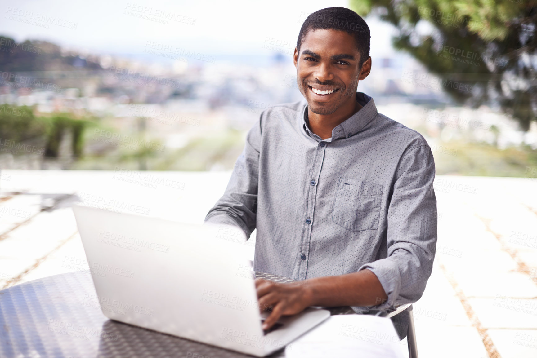 Buy stock photo Shot of a handsome young man working on his laptop outside