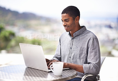 Buy stock photo Shot of a handsome young man working on his laptop outside