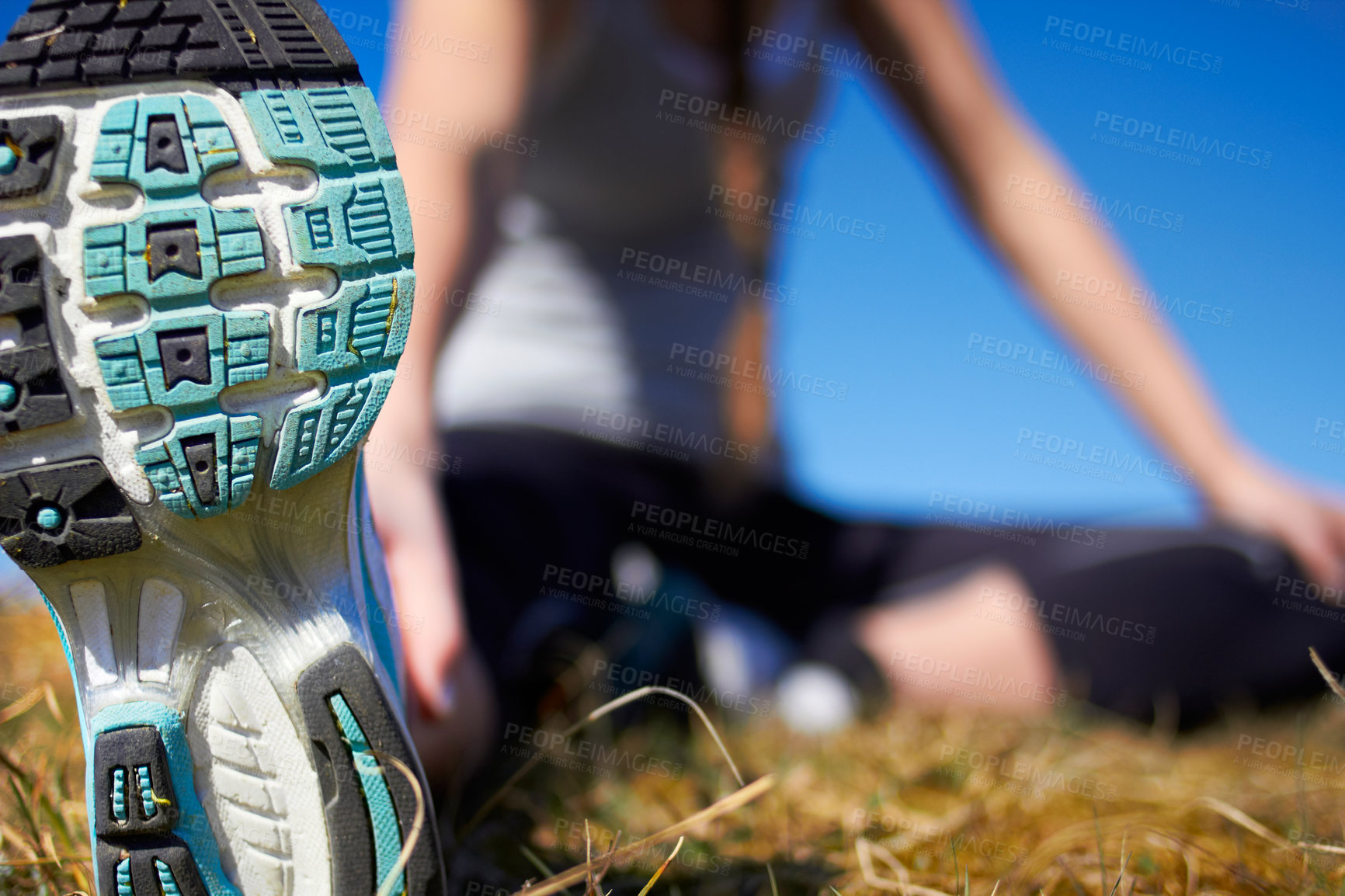 Buy stock photo Shoe sole closeup, training and space for mockup by blurred background with woman stretching legs. Sneakers, zoom and mock up for wellness, running or exercise with girl on grass for healthy workout