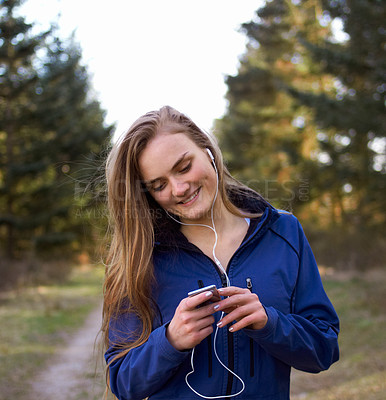 Buy stock photo Shot of an attractive and sporty young woman preparing her playlist before a run