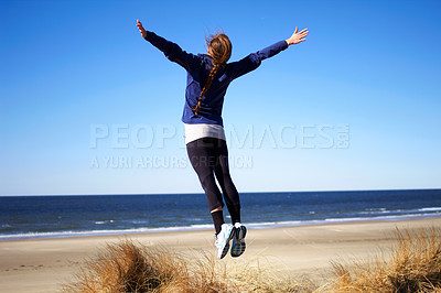 Buy stock photo Rearview shot of a young woman jumping into the air at the beach