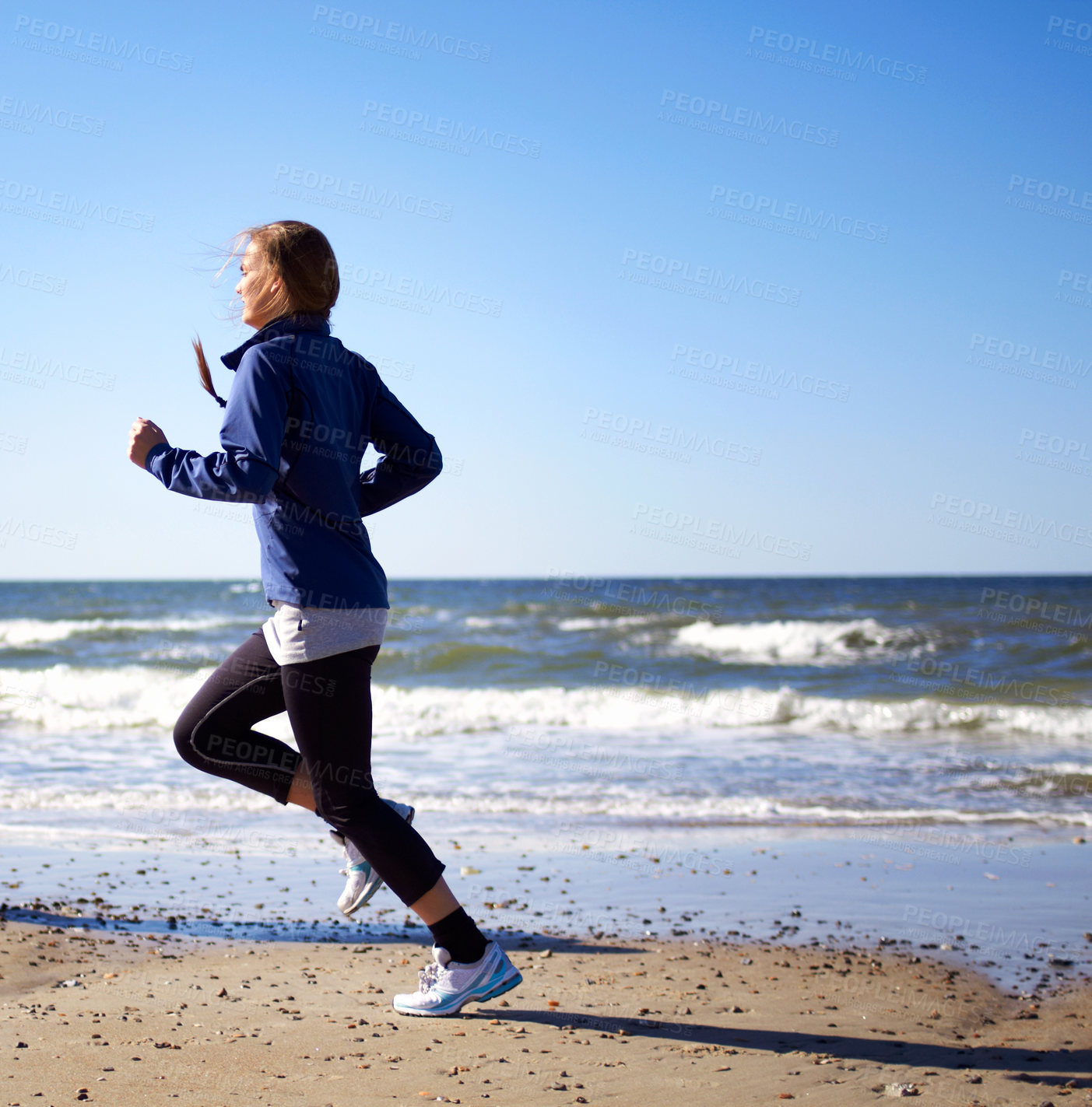 Buy stock photo A sporty young woman  running along the beach