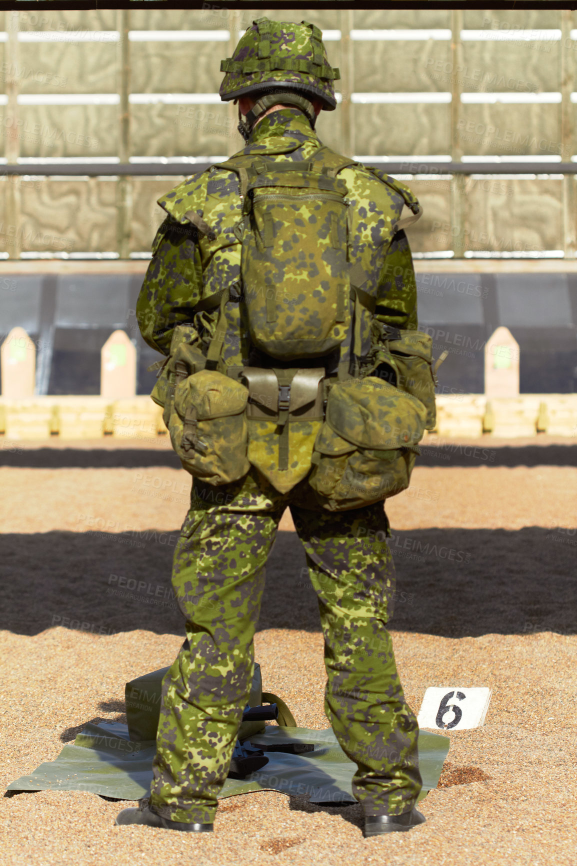 Buy stock photo Rearview shot of a young soldier in his uniform with his gear in front of him