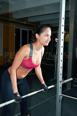 Buy stock photo Shot of an attractive young woman pumping iron in the gym