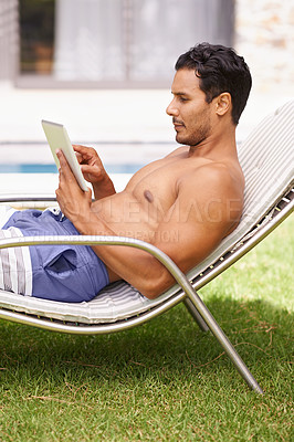 Buy stock photo Shot of a man reading a book while sitting in a deckchair