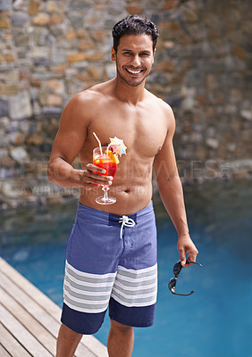 Buy stock photo Portrait of a handsome man by a pool holding a cocktail