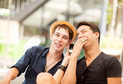Buy stock photo Shot of two friends sharing a phone call outdoors