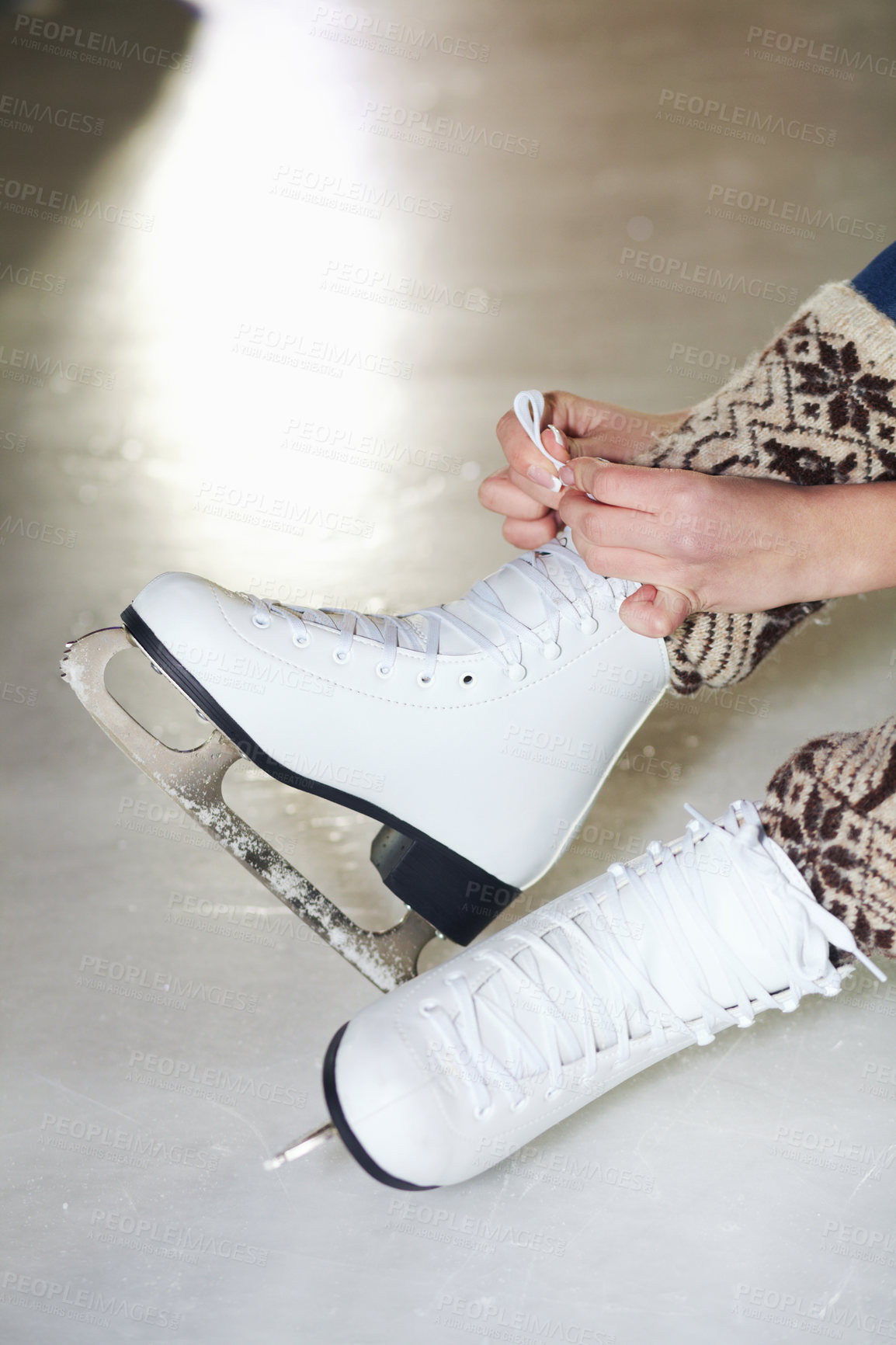 Buy stock photo Cropped shot of a woman sitting on ice tying up her ice skates