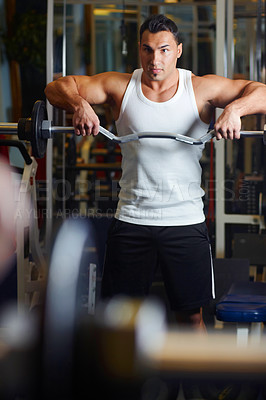 Buy stock photo A young man lifting a dumbbell at the gym